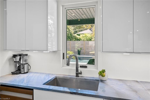 kitchen featuring white cabinetry, sink, and dark stone counters