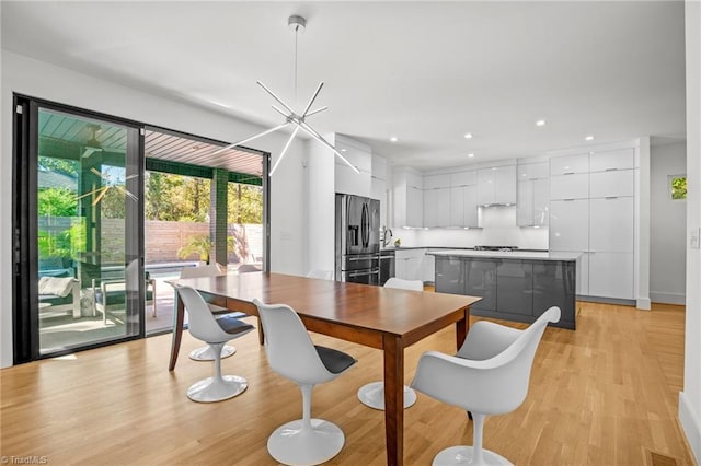 dining space with light hardwood / wood-style floors, sink, and a chandelier