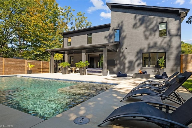 back of property with a patio area and a fenced in pool