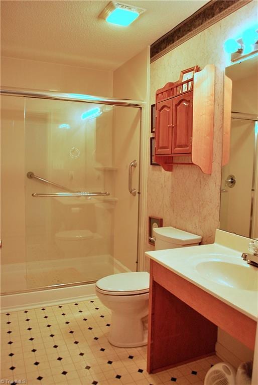 full bath with a stall shower, vanity, toilet, and a textured ceiling
