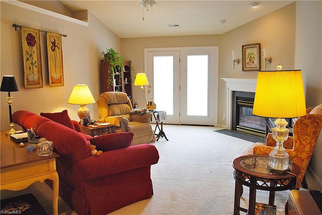 living area with a ceiling fan, carpet, a fireplace with flush hearth, and visible vents