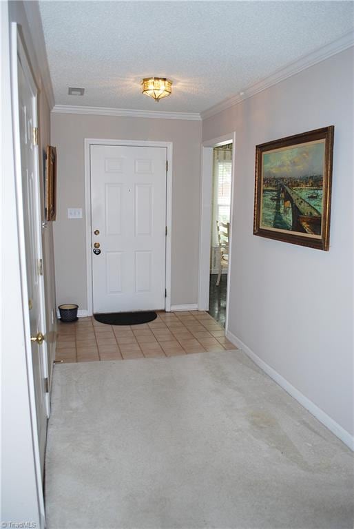 entryway with light tile patterned floors, crown molding, visible vents, baseboards, and light colored carpet