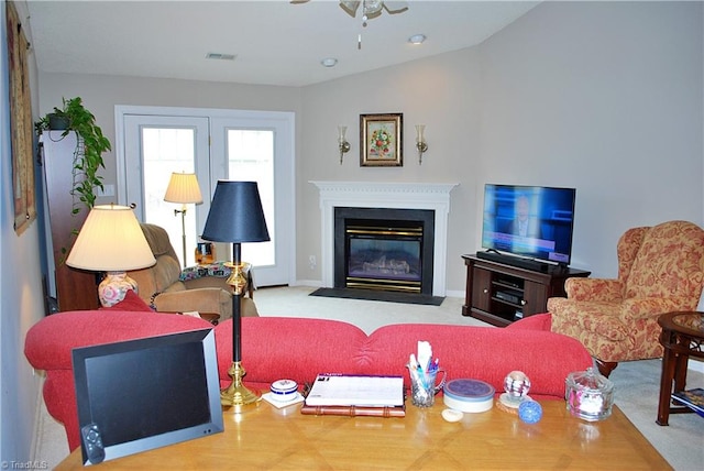 living area with a fireplace with flush hearth, carpet flooring, a ceiling fan, and visible vents