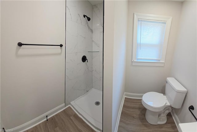 bathroom featuring hardwood / wood-style flooring, tiled shower, and toilet