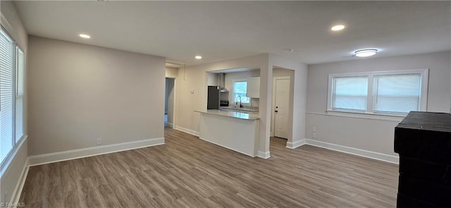 unfurnished living room featuring sink, hardwood / wood-style flooring, and a wealth of natural light