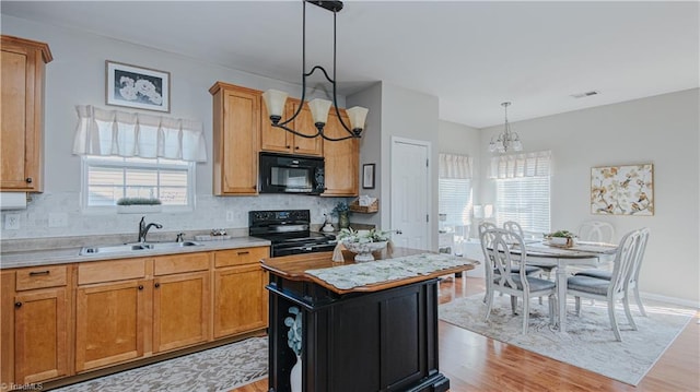 kitchen featuring an inviting chandelier, black appliances, light countertops, and a sink