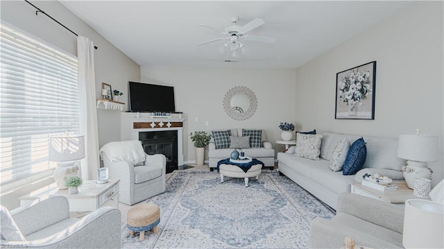 living area with a fireplace with flush hearth and a ceiling fan