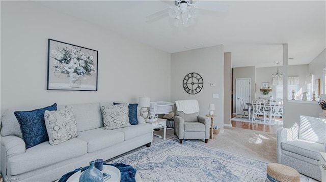 living room with visible vents, ceiling fan with notable chandelier, and carpet floors