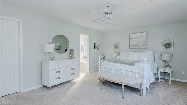 bedroom featuring ensuite bath, light colored carpet, a ceiling fan, and baseboards