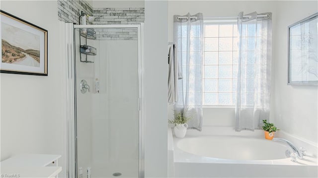 full bathroom featuring a wealth of natural light, a garden tub, and a stall shower