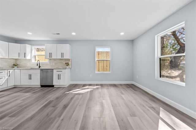 kitchen featuring stainless steel dishwasher, white cabinets, baseboards, and tasteful backsplash