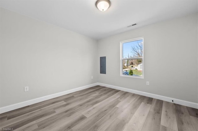 spare room with electric panel, visible vents, baseboards, and wood finished floors