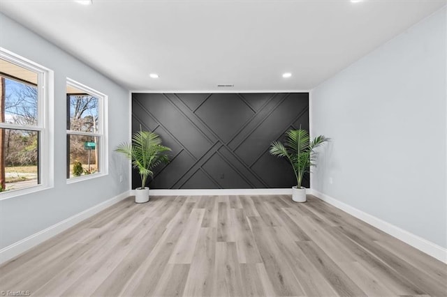 empty room featuring recessed lighting, light wood-style flooring, an accent wall, and baseboards