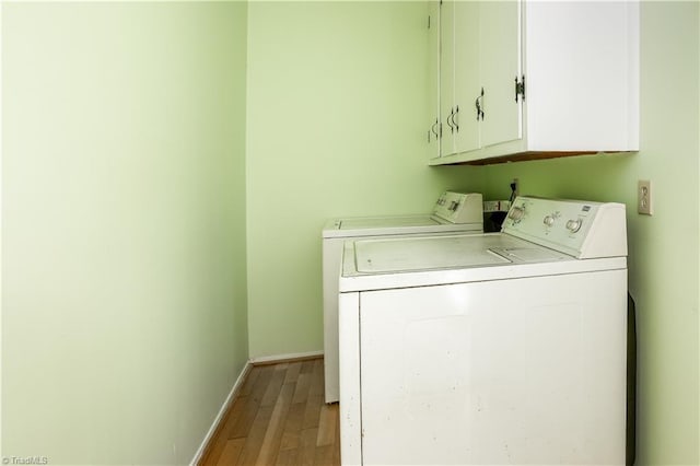 laundry area with light wood-type flooring, cabinets, and washing machine and clothes dryer