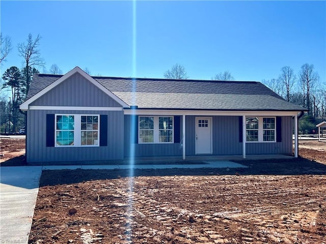 single story home with covered porch, roof with shingles, and board and batten siding