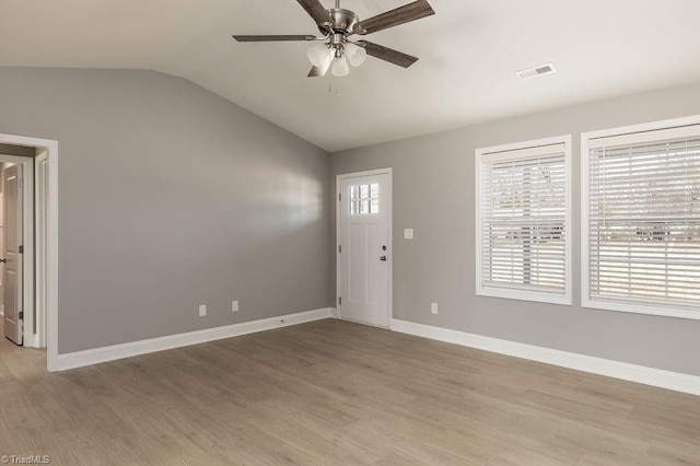 foyer with lofted ceiling, light wood-style floors, visible vents, and a wealth of natural light