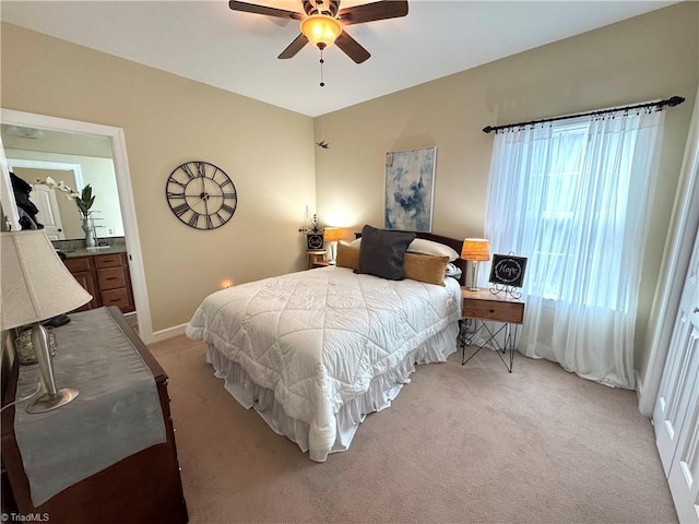 bedroom with ceiling fan, light colored carpet, and connected bathroom