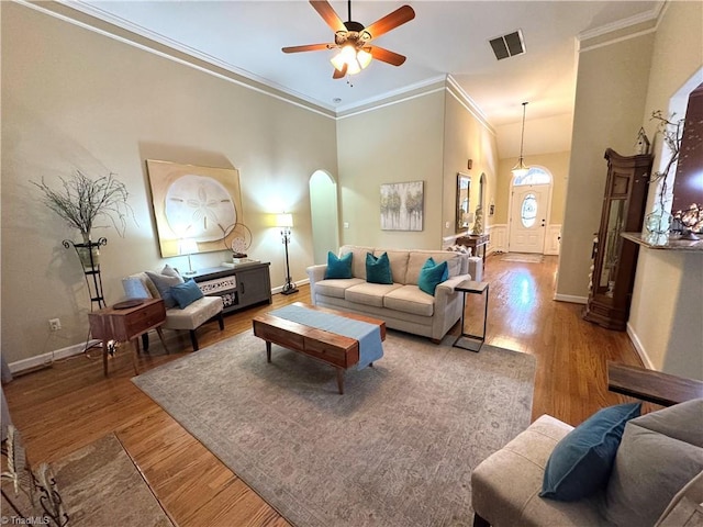 living room featuring ceiling fan, a towering ceiling, crown molding, and hardwood / wood-style flooring