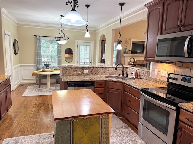 kitchen with appliances with stainless steel finishes, pendant lighting, ornamental molding, and sink