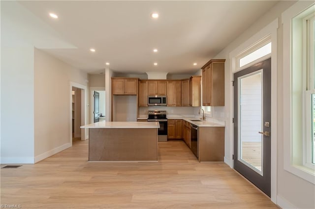 kitchen featuring stainless steel microwave, range with electric cooktop, a kitchen island, dishwasher, and a sink