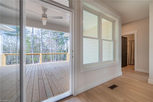 doorway featuring visible vents, baseboards, a ceiling fan, and wood finished floors