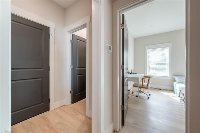 hallway featuring baseboards and light wood finished floors