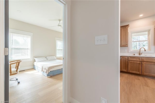 interior space featuring connected bathroom, baseboards, light wood-type flooring, recessed lighting, and a sink