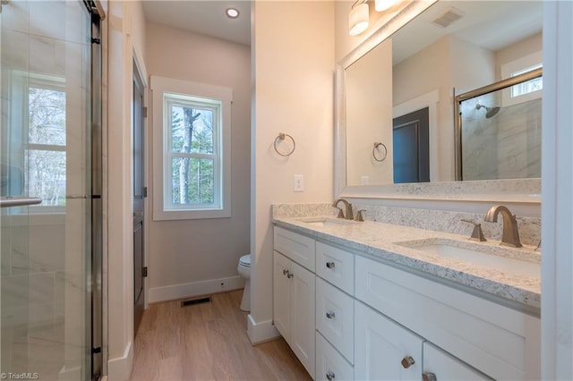 full bathroom with visible vents, toilet, a stall shower, a sink, and double vanity