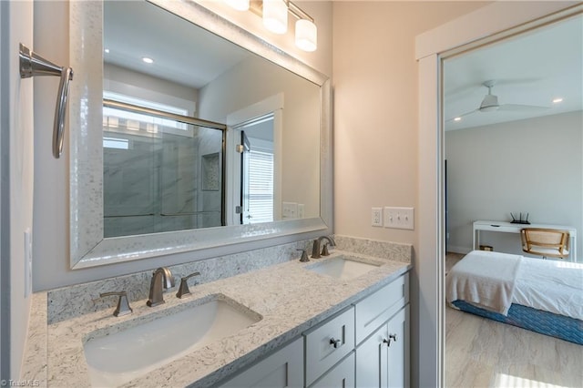 full bathroom featuring a shower stall, wood finished floors, double vanity, and a sink