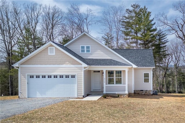 view of front of property with a porch, roof with shingles, gravel driveway, a front yard, and an attached garage