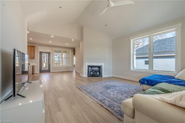 living room with a fireplace, baseboards, light wood-style floors, and a ceiling fan