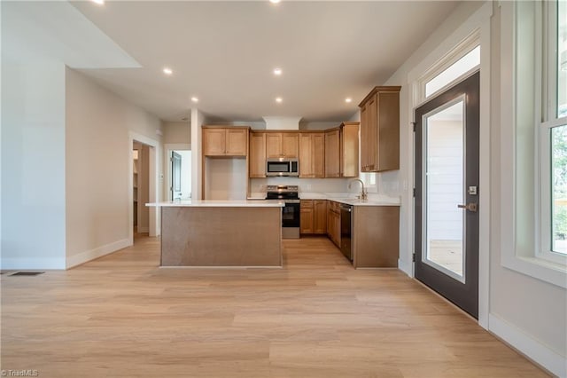 kitchen featuring light wood-type flooring, stainless steel appliances, visible vents, and a center island