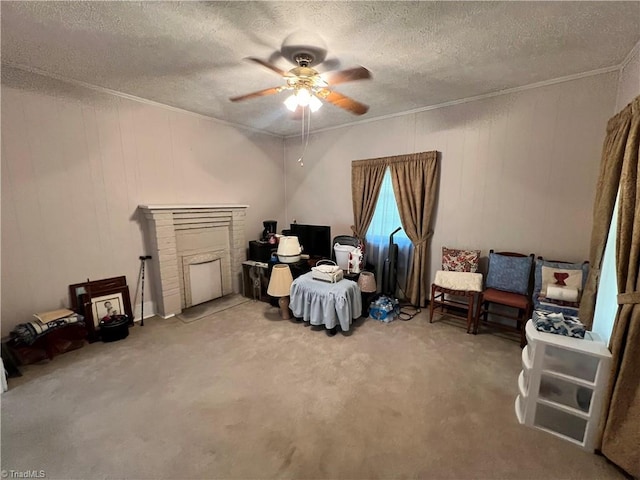 living area with ornamental molding, a ceiling fan, carpet flooring, a textured ceiling, and a fireplace