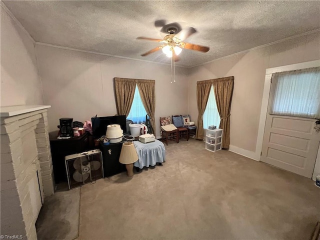 living area featuring a textured ceiling, ornamental molding, ceiling fan, and carpet floors