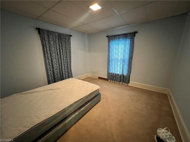 bedroom featuring carpet, a drop ceiling, and baseboards
