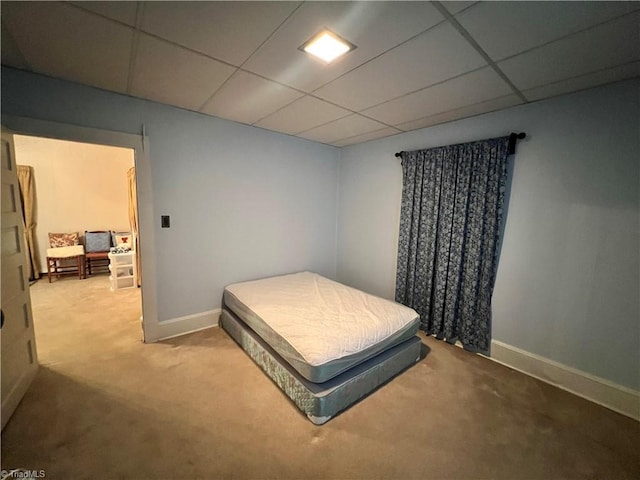 carpeted bedroom with a drop ceiling and baseboards