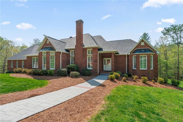view of front of house featuring brick siding, a front lawn, and a chimney