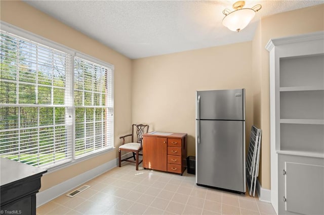 kitchen with a wealth of natural light, freestanding refrigerator, a textured ceiling, and visible vents