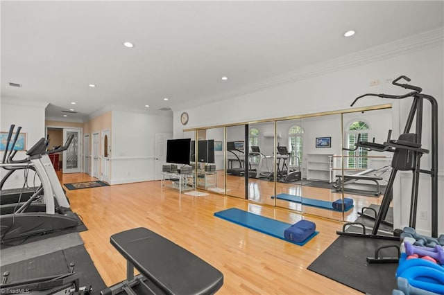 exercise room featuring crown molding, recessed lighting, wood finished floors, and visible vents