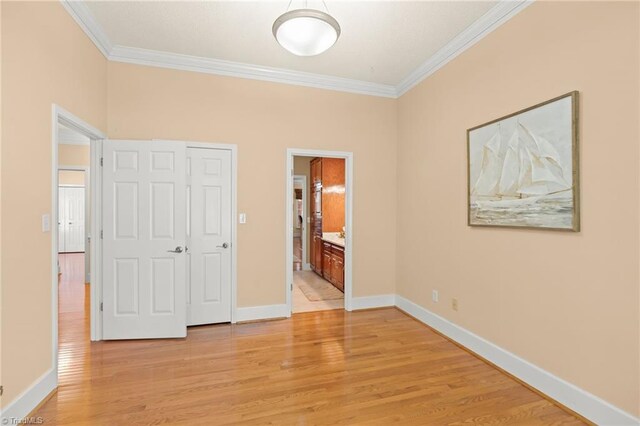 unfurnished bedroom featuring crown molding, baseboards, and light wood-type flooring
