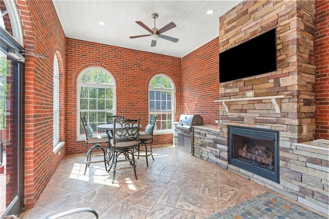 view of patio featuring an outdoor stone fireplace, ceiling fan, and a grill
