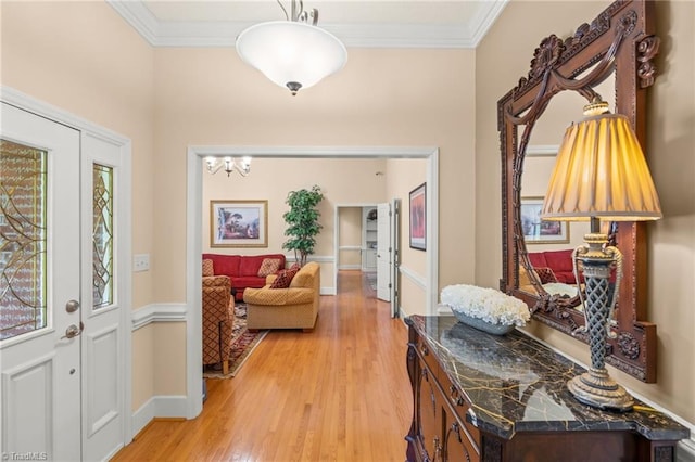 entrance foyer with baseboards, ornamental molding, and light wood-style flooring