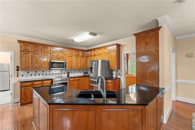 kitchen with brown cabinets, appliances with stainless steel finishes, a sink, and light wood-style flooring
