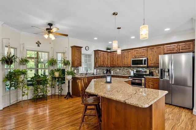 2515 E Woodlyn Way, Greensboro, NC 27407 - kitchen with stainless steel appliances, a ceiling fan, a center island, light stone countertops, and tasteful backsplash