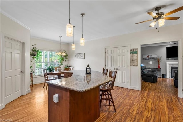 2515 E Woodlyn Way, Greensboro, NC 27407 - kitchen with a kitchen bar, ceiling fan, light wood-style flooring, crown molding, and light stone counters