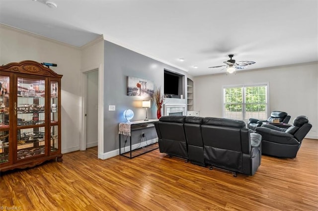 2515 E Woodlyn Way, Greensboro, NC 27407 - living room featuring wood finished floors, ornamental molding, a fireplace, a ceiling fan, and baseboards