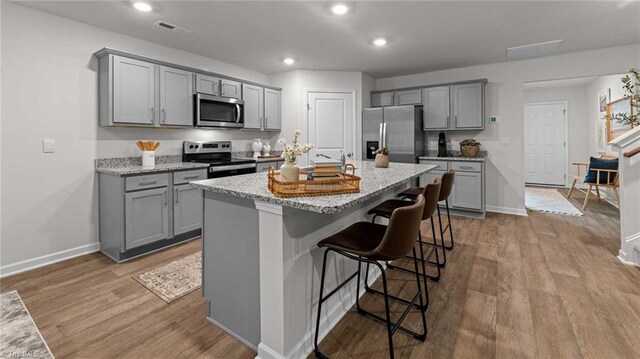 144 Rose Wind Way, Mayodan, NC 27027 - kitchen featuring a center island with sink, appliances with stainless steel finishes, wood finished floors, and gray cabinets