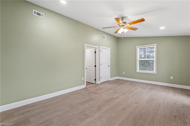 spare room featuring light wood-type flooring, vaulted ceiling, and ceiling fan