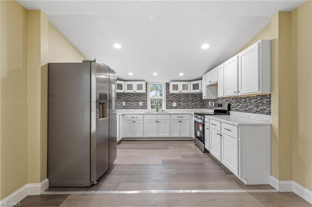 kitchen with light stone counters, stainless steel appliances, sink, light hardwood / wood-style flooring, and white cabinetry