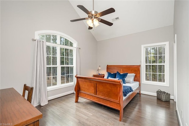 bedroom featuring ceiling fan, dark hardwood / wood-style floors, high vaulted ceiling, and multiple windows